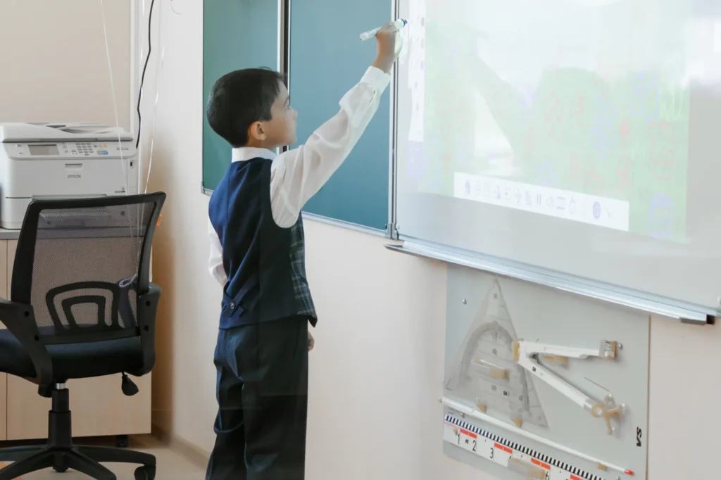 Élève écrivant sur un tableau interactif Ulmann à l’école